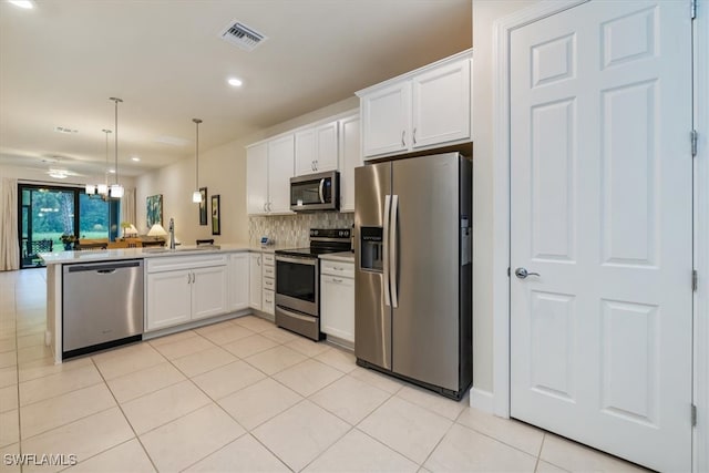 kitchen with stainless steel appliances, decorative light fixtures, kitchen peninsula, sink, and white cabinets