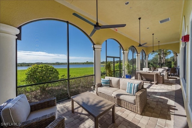 sunroom featuring lofted ceiling, a water view, and ceiling fan