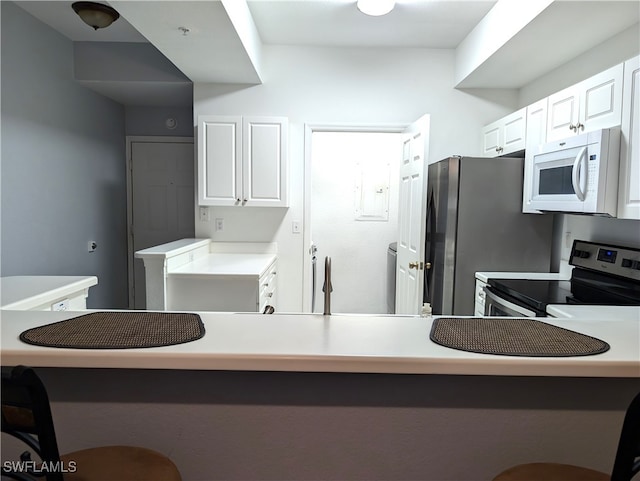 kitchen featuring white cabinets, stainless steel appliances, kitchen peninsula, and a breakfast bar