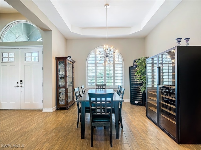 dining room with an inviting chandelier, a tray ceiling, and light hardwood / wood-style flooring