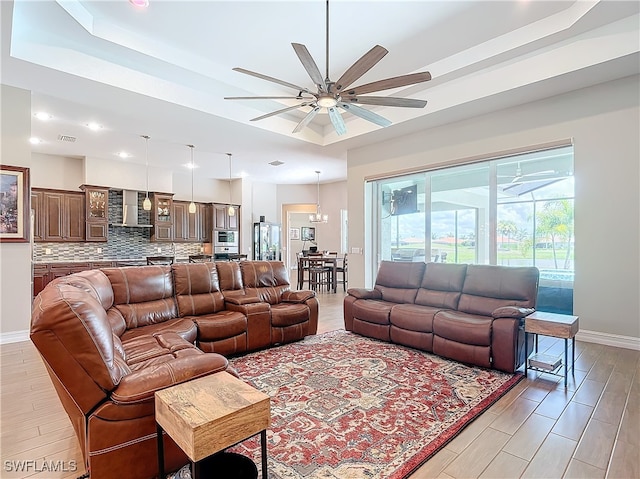 living room with a tray ceiling, light hardwood / wood-style flooring, and ceiling fan