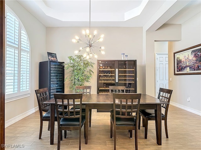 dining room featuring a tray ceiling, a chandelier, and light wood-type flooring