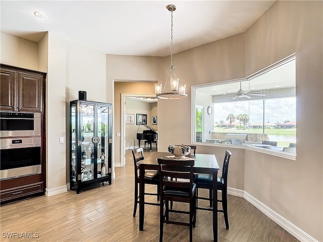 dining area with light hardwood / wood-style flooring and ceiling fan with notable chandelier