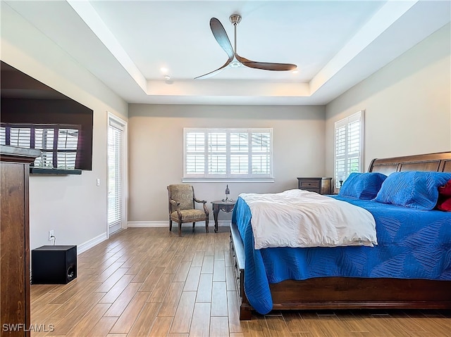 bedroom featuring hardwood / wood-style flooring, a raised ceiling, and ceiling fan