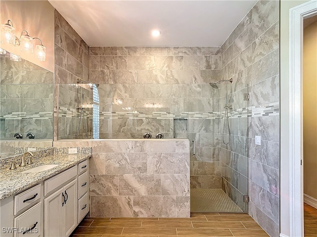 bathroom featuring vanity, a shower with shower door, and tile walls