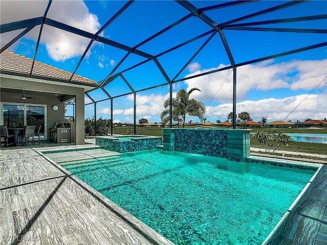 view of pool with glass enclosure, ceiling fan, pool water feature, a water view, and a patio