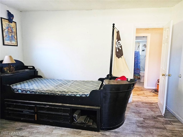 bedroom with ensuite bathroom and wood-type flooring