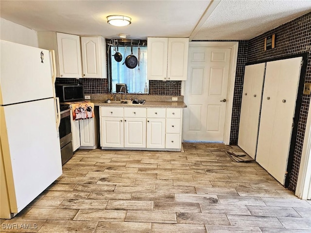 12474 Poem Ave, Punta Gorda, FL 33955 - kitchen featuring freestanding refrigerator, black microwave, white cabinetry, light wood finished floors, and backsplash
