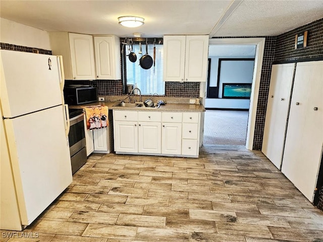 kitchen with white fridge, white cabinetry, and sink