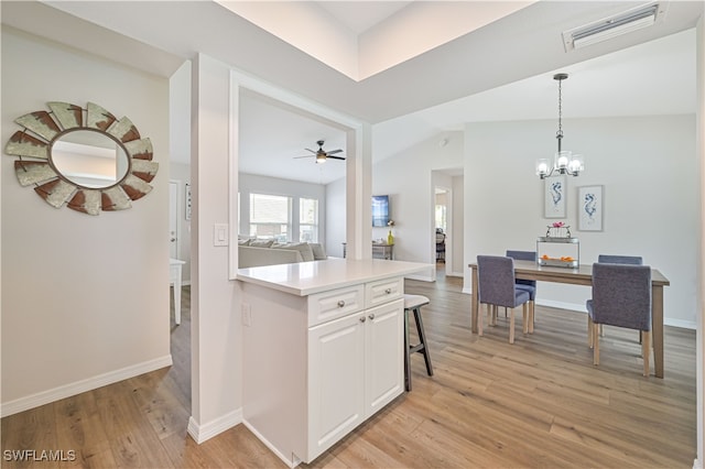 kitchen featuring ceiling fan with notable chandelier, light hardwood / wood-style floors, and white cabinetry