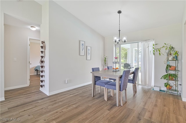 dining space featuring light wood-type flooring, a chandelier, and vaulted ceiling