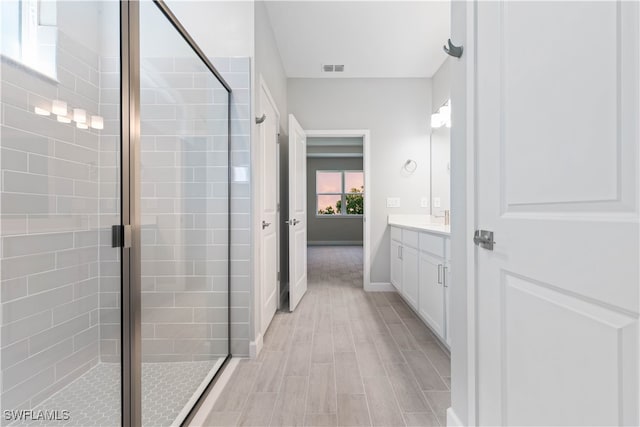 bathroom featuring hardwood / wood-style floors, a shower with door, and vanity