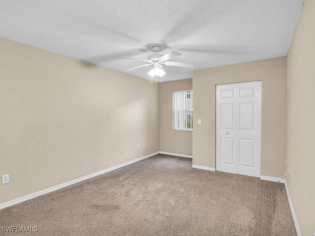 unfurnished room featuring a textured ceiling, ceiling fan, and carpet floors