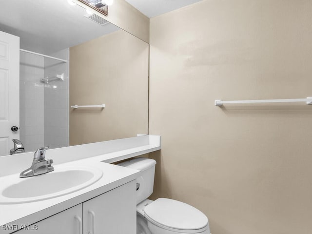 bathroom with vanity, toilet, and tiled shower