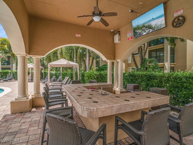 view of patio with a gazebo, ceiling fan, and exterior bar