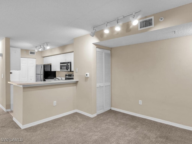 kitchen with light carpet, appliances with stainless steel finishes, kitchen peninsula, and white cabinetry