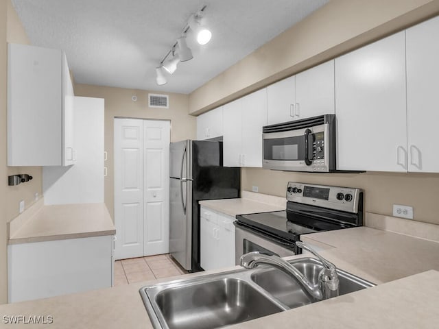 kitchen featuring appliances with stainless steel finishes, white cabinetry, sink, and track lighting