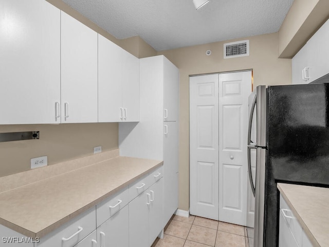 kitchen featuring white cabinets, stainless steel fridge, a textured ceiling, and light tile patterned flooring