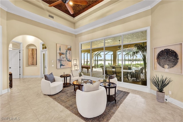 sitting room featuring a towering ceiling, ceiling fan, a raised ceiling, and ornamental molding