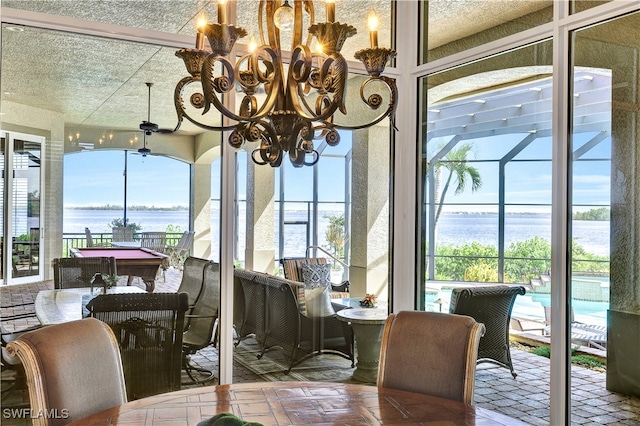 sunroom / solarium with a chandelier and a water view