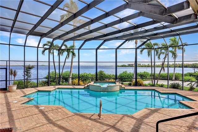 view of pool featuring glass enclosure, a water view, a patio area, and an in ground hot tub