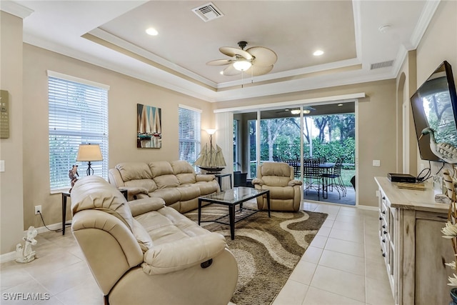 living area featuring a ceiling fan, visible vents, a wealth of natural light, a tray ceiling, and crown molding