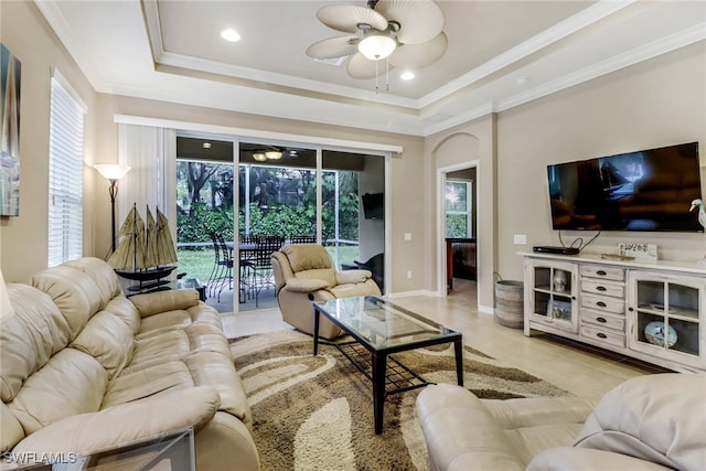 living area featuring light tile patterned floors, a tray ceiling, a ceiling fan, and crown molding