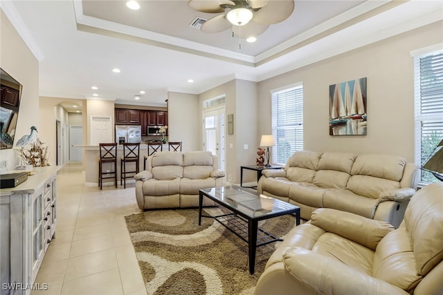 living area featuring light tile patterned floors, ceiling fan, recessed lighting, ornamental molding, and a raised ceiling