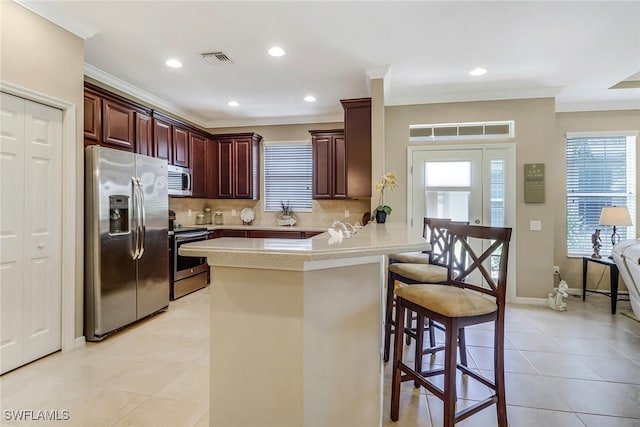 kitchen with a peninsula, visible vents, light countertops, appliances with stainless steel finishes, and a kitchen bar