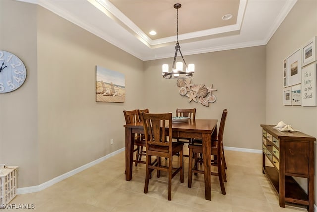 dining area featuring a chandelier, a raised ceiling, crown molding, and baseboards