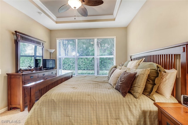 bedroom with ceiling fan, light colored carpet, baseboards, ornamental molding, and a raised ceiling