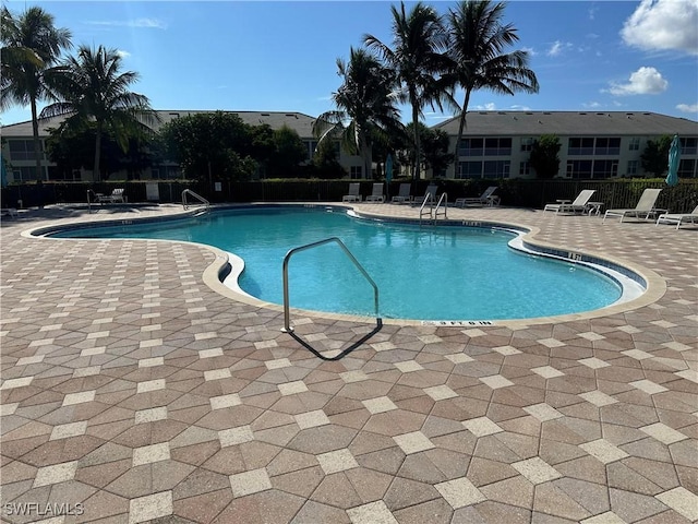 community pool with a patio area and fence