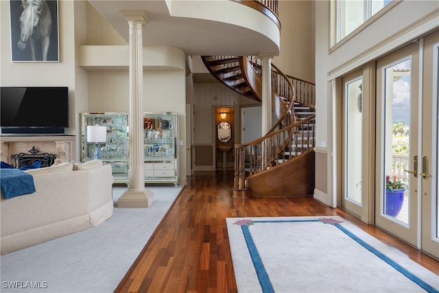 foyer with french doors, hardwood / wood-style floors, ornate columns, and a high ceiling