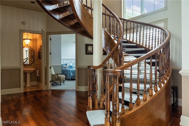 stairs featuring a towering ceiling, ornamental molding, hardwood / wood-style flooring, and sink