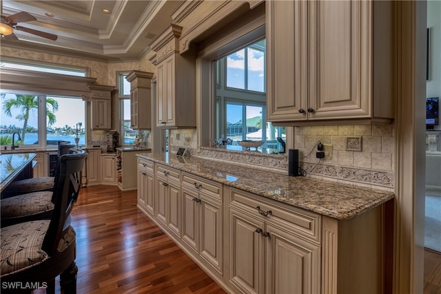 kitchen featuring coffered ceiling, dark hardwood / wood-style floors, light stone countertops, crown molding, and ceiling fan