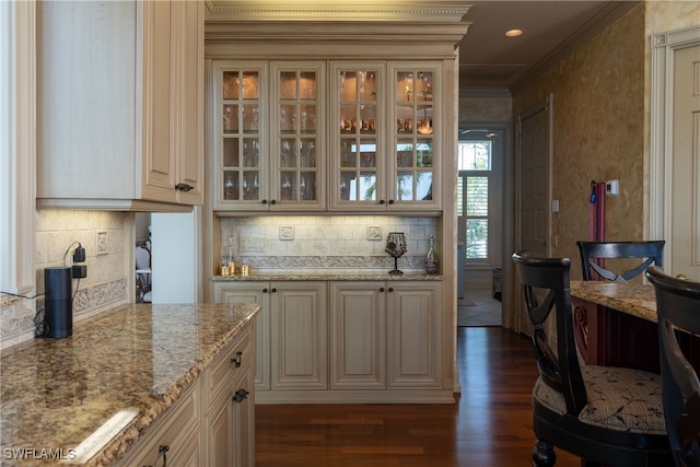 bar with built in desk, ornamental molding, tasteful backsplash, dark hardwood / wood-style flooring, and light stone countertops