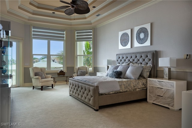 carpeted bedroom featuring a tray ceiling, crown molding, and ceiling fan