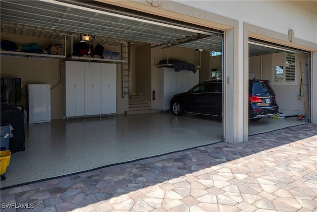 garage with white refrigerator, a garage door opener, and a carport