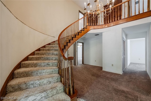 stairway featuring a high ceiling, carpet flooring, and a chandelier