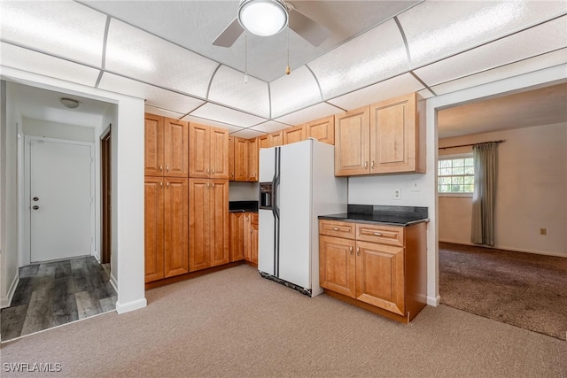 kitchen featuring light colored carpet, white fridge with ice dispenser, and ceiling fan