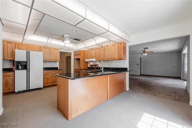 kitchen featuring light colored carpet, white refrigerator with ice dispenser, sink, kitchen peninsula, and ceiling fan