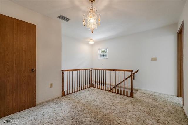 carpeted spare room with an inviting chandelier