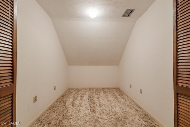 bonus room featuring lofted ceiling, carpet flooring, and a textured ceiling