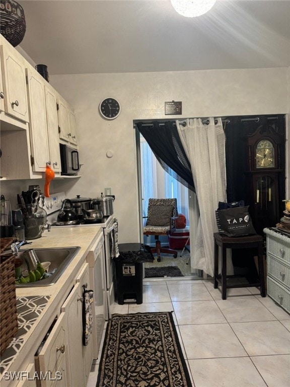 kitchen with sink, stainless steel stove, and light tile patterned flooring