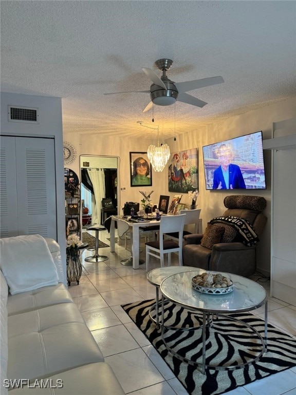 tiled living room with ceiling fan with notable chandelier and a textured ceiling