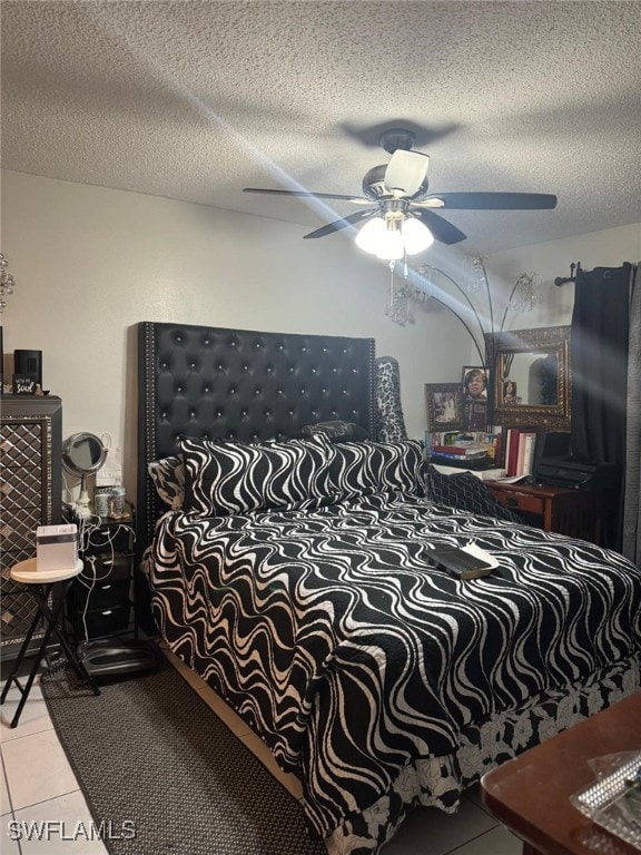 bedroom with ceiling fan, a textured ceiling, and tile patterned floors