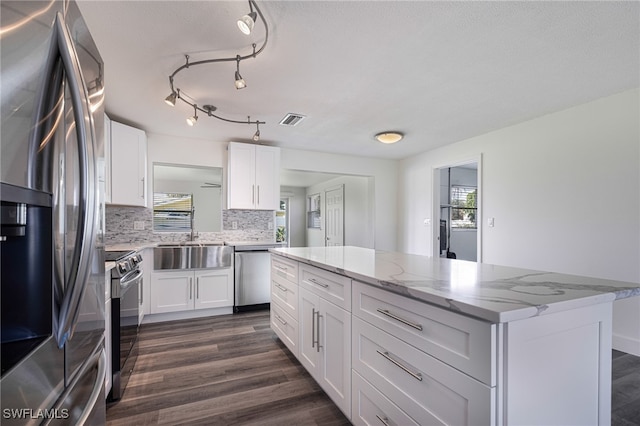 kitchen featuring backsplash, white cabinets, sink, light stone countertops, and appliances with stainless steel finishes