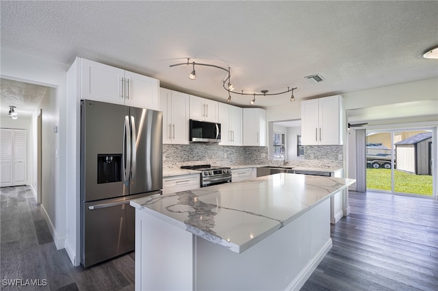 kitchen with light stone counters, a center island, white cabinets, and appliances with stainless steel finishes