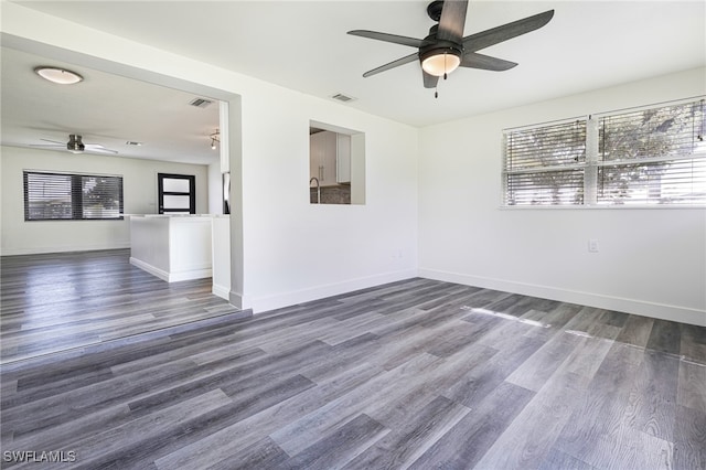 unfurnished room featuring a wealth of natural light, ceiling fan, and dark hardwood / wood-style flooring