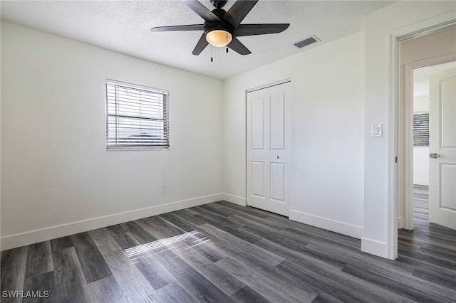 unfurnished bedroom with dark hardwood / wood-style flooring, ceiling fan, a closet, and a textured ceiling